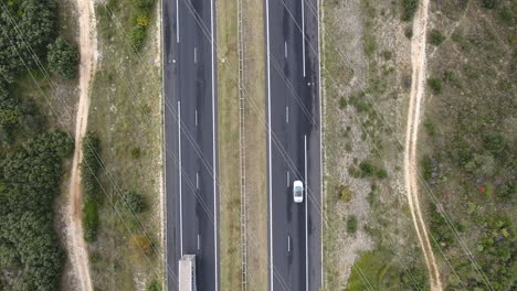 Aerial-fix-shot-above-a-highway-with-trucks-and-car-.-Electric-lines-and-dirt